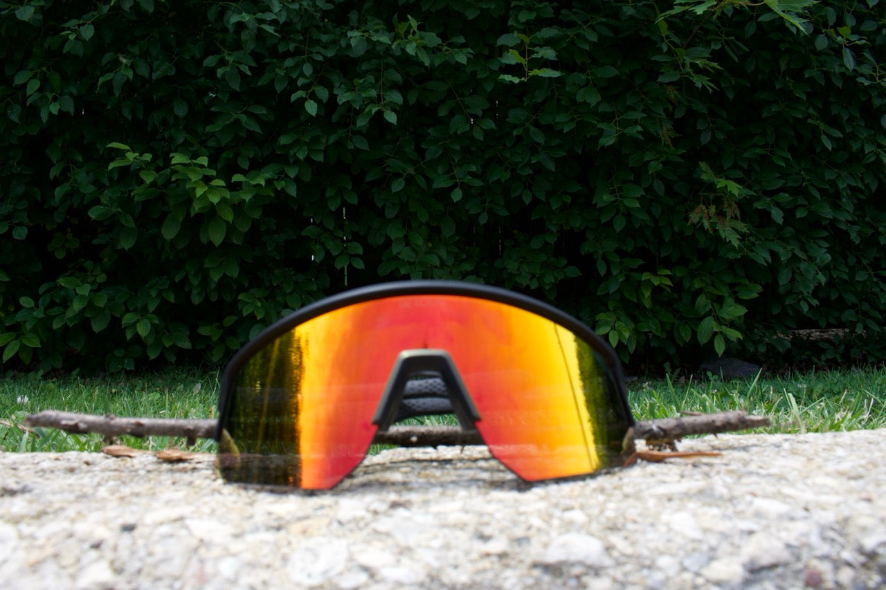 Man wearing mirrored goggles and gray beanie, holding skis in a snowy setting.