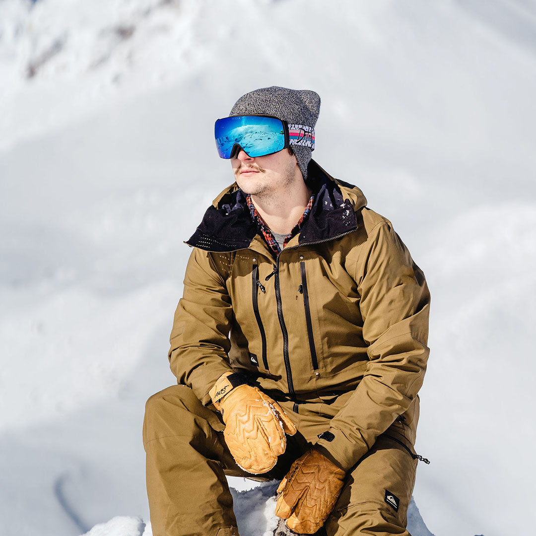 Person holding ski goggles with interchangeable lens.