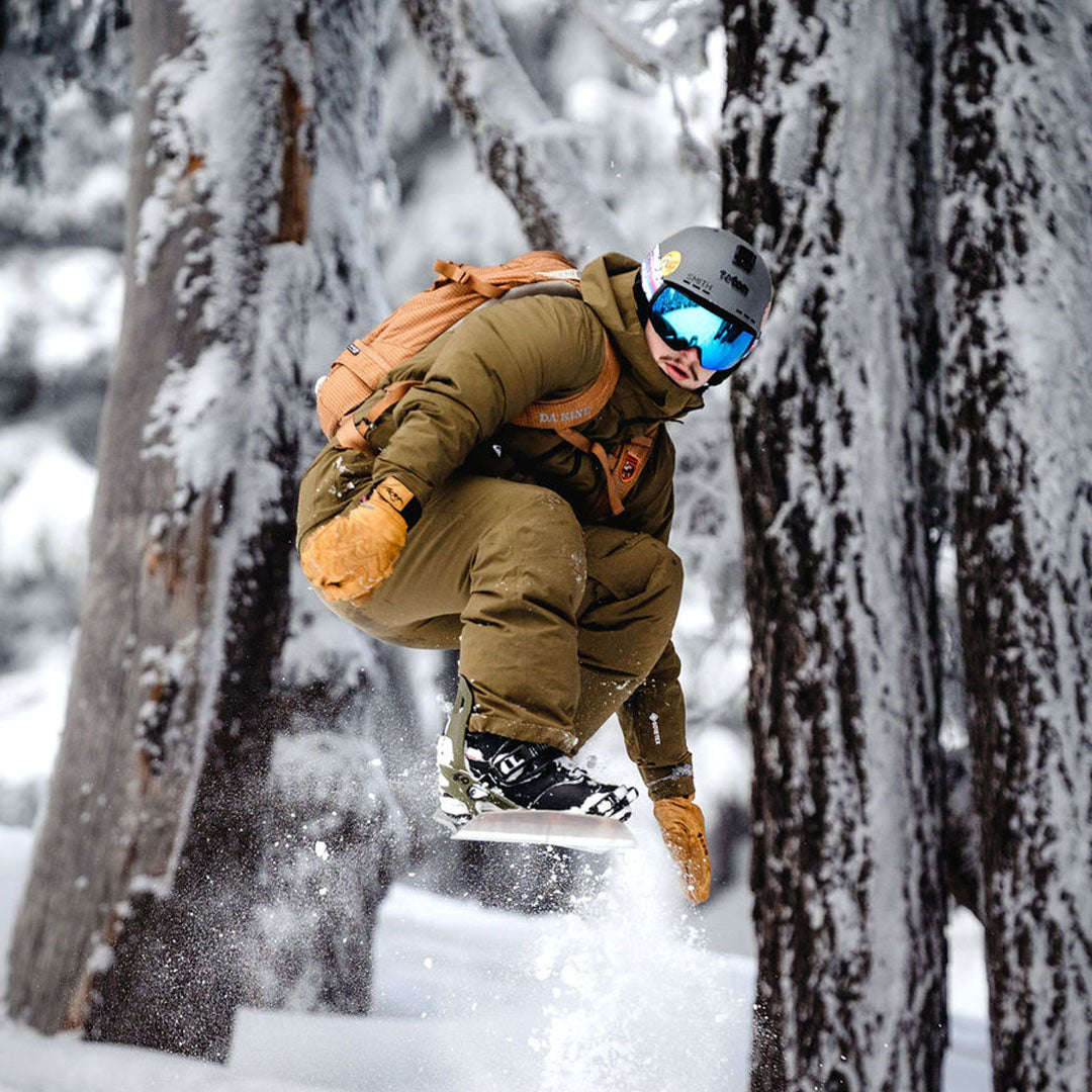 Snowboarder carving through powder in snowy terrain.